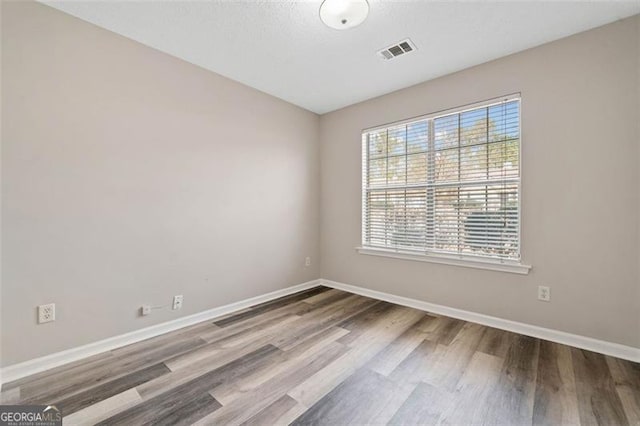 spare room featuring hardwood / wood-style floors and plenty of natural light