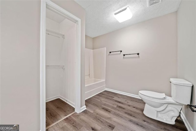 bathroom featuring a textured ceiling, wood-type flooring, and toilet