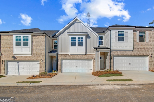 townhome / multi-family property with an attached garage, brick siding, board and batten siding, and concrete driveway