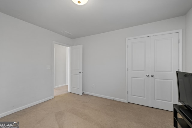 unfurnished bedroom featuring a closet, carpet, visible vents, and baseboards