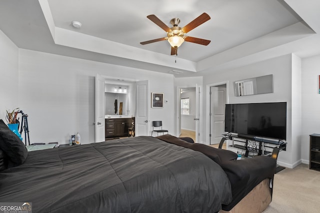 bedroom featuring light carpet, baseboards, a ceiling fan, connected bathroom, and a tray ceiling