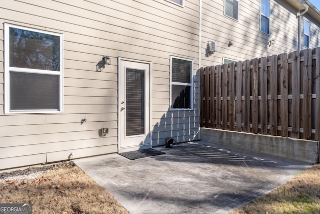 view of exterior entry with a patio and fence