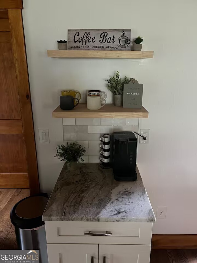 bar featuring white cabinetry, hardwood / wood-style floors, and decorative backsplash