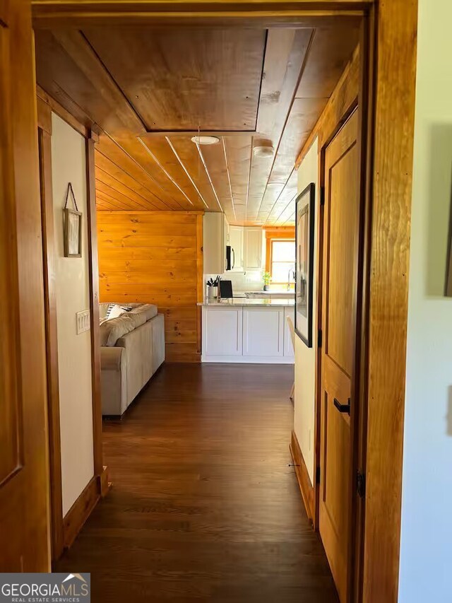 hallway featuring wooden walls, dark hardwood / wood-style floors, and wood ceiling