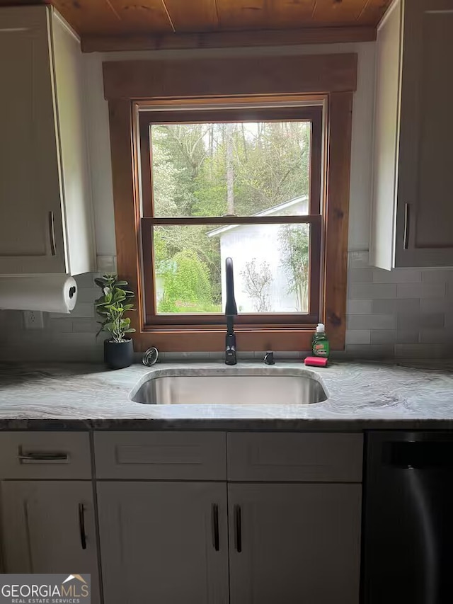 kitchen with decorative backsplash, sink, light stone counters, and dishwasher