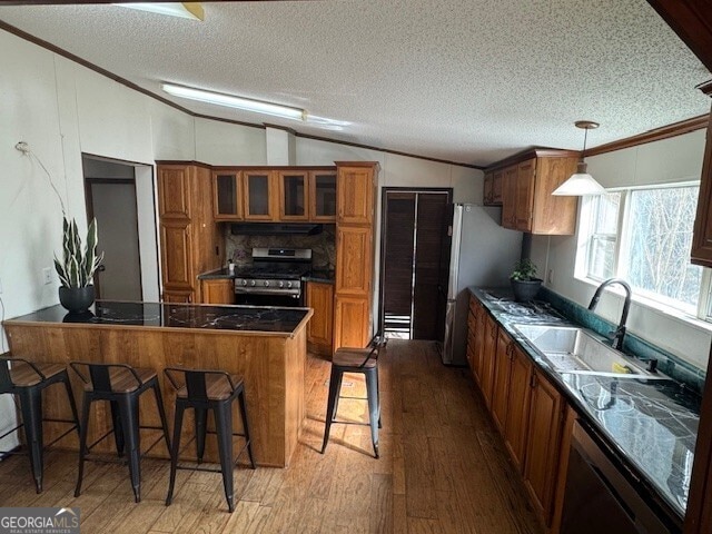 kitchen with a sink, brown cabinets, a kitchen breakfast bar, stainless steel appliances, and glass insert cabinets