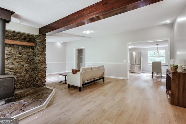 4419 New Kings Bridge Rd, Nicholson, GA 30565 - living room featuring a wood stove, light wood-style floors, beamed ceiling, and baseboards