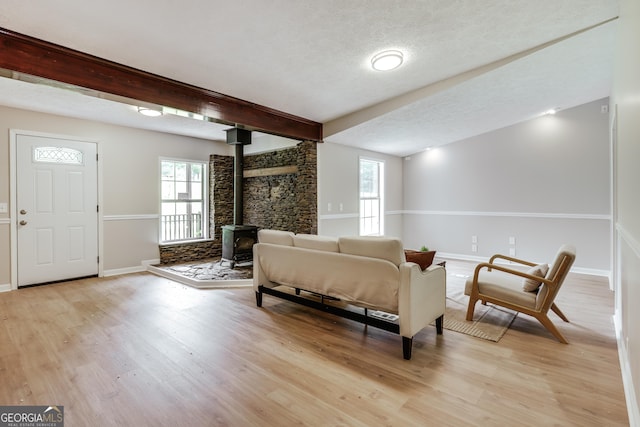 4419 New Kings Bridge Rd, Nicholson, GA 30565 - living area with a wood stove, light wood-type flooring, baseboards, beam ceiling, and a textured ceiling