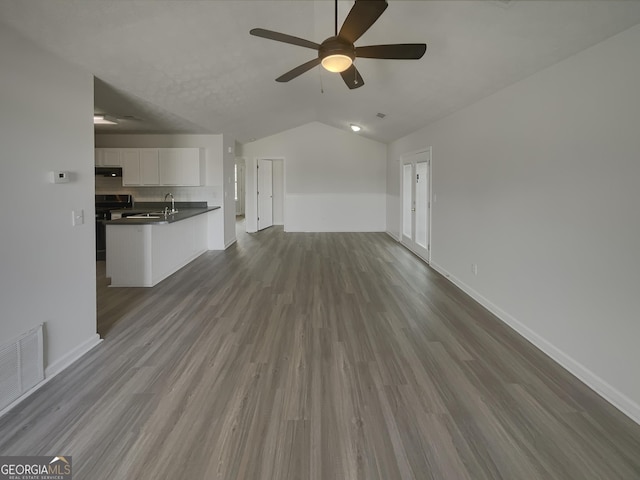 unfurnished living room with ceiling fan, sink, wood-type flooring, and lofted ceiling