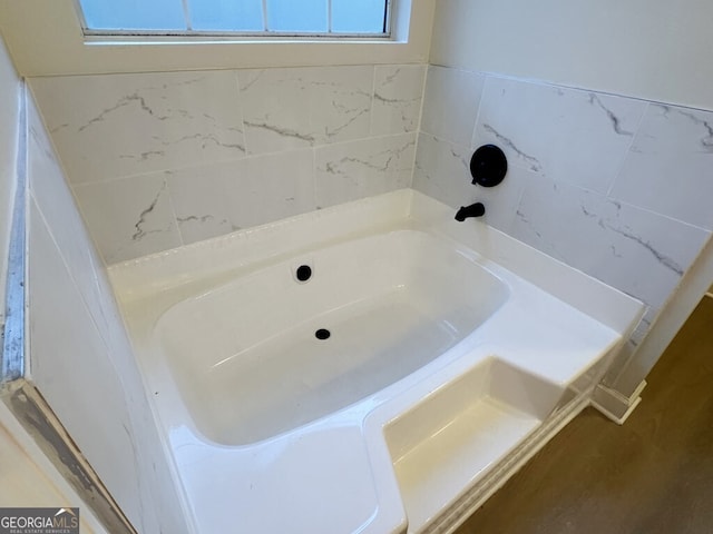 bathroom with a bathing tub and hardwood / wood-style flooring