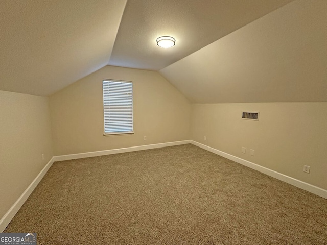 bonus room with a textured ceiling, vaulted ceiling, and carpet flooring