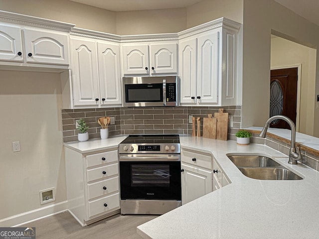 kitchen with light hardwood / wood-style flooring, sink, backsplash, white cabinetry, and stainless steel appliances