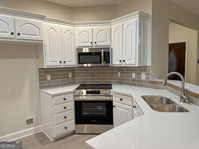 kitchen with light wood-type flooring, sink, appliances with stainless steel finishes, white cabinets, and decorative backsplash