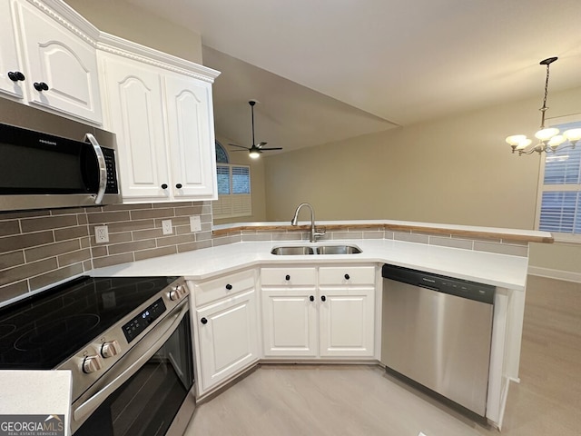 kitchen with kitchen peninsula, white cabinetry, stainless steel appliances, and sink