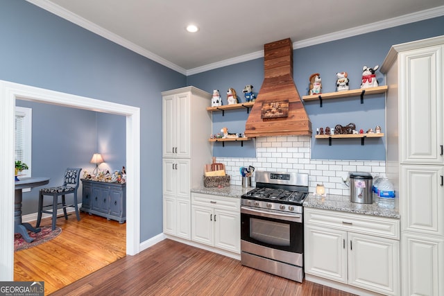 kitchen with premium range hood, dark wood-type flooring, white cabinets, gas range, and tasteful backsplash