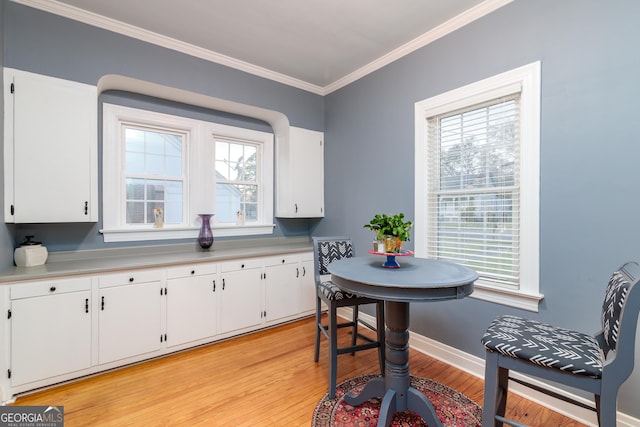 dining area with a wealth of natural light, crown molding, and light hardwood / wood-style floors