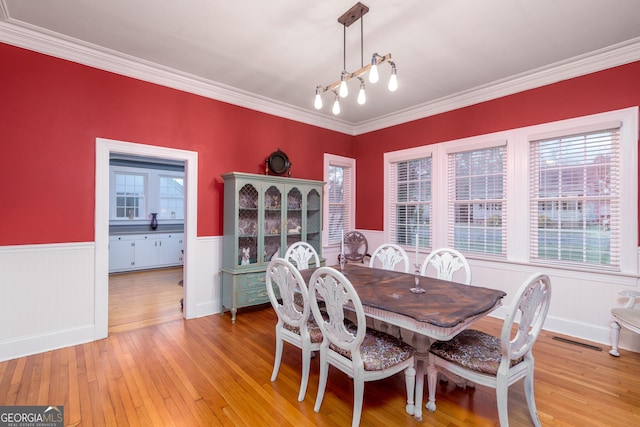 dining room with ornamental molding, plenty of natural light, light hardwood / wood-style floors, and an inviting chandelier