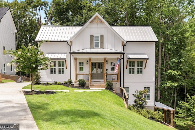 modern farmhouse with covered porch, a front lawn, and french doors