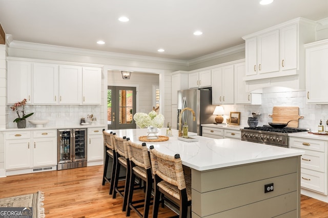 kitchen with an island with sink, a breakfast bar, stainless steel refrigerator with ice dispenser, wine cooler, and white cabinets