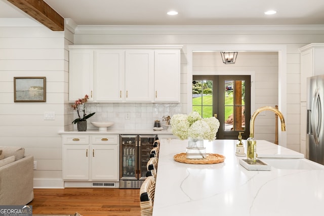 kitchen with wood-type flooring, white cabinets, sink, stainless steel fridge with ice dispenser, and wine cooler