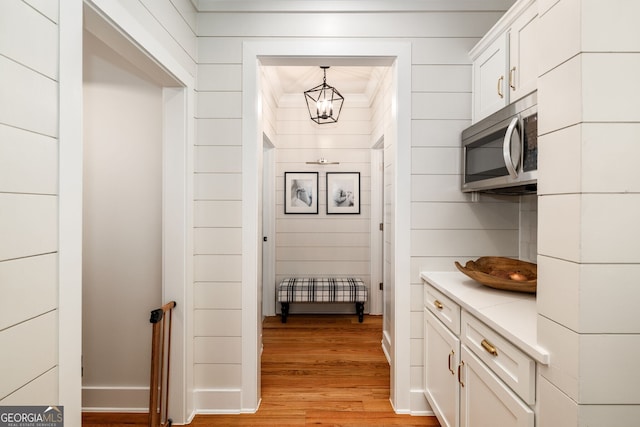 interior space with white cabinetry, light hardwood / wood-style floors, and pendant lighting