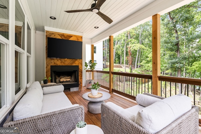 sunroom / solarium featuring ceiling fan, a large fireplace, and wood ceiling