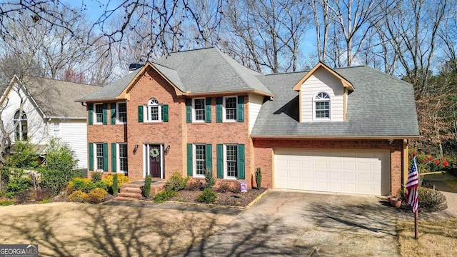 colonial-style house with a shingled roof, brick siding, driveway, and an attached garage