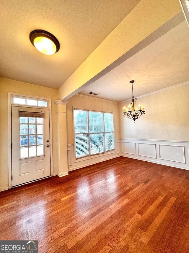 entryway featuring a textured ceiling, ornamental molding, hardwood / wood-style flooring, and an inviting chandelier