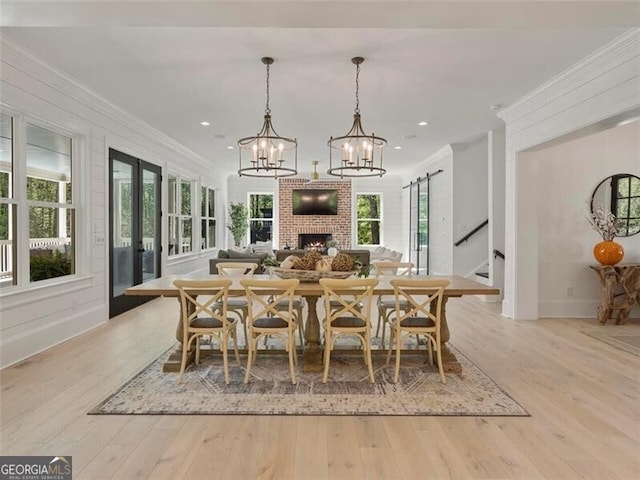 dining space featuring ornamental molding, a barn door, and light hardwood / wood-style floors