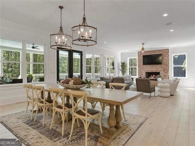 dining space featuring plenty of natural light, light hardwood / wood-style floors, crown molding, and a brick fireplace