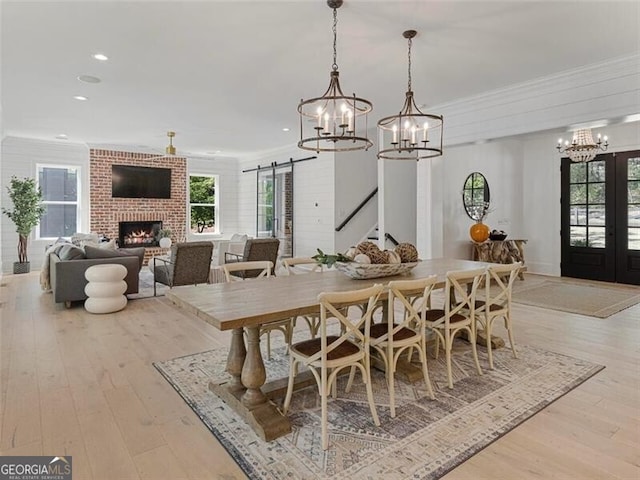 dining room featuring a barn door, crown molding, french doors, and light hardwood / wood-style flooring