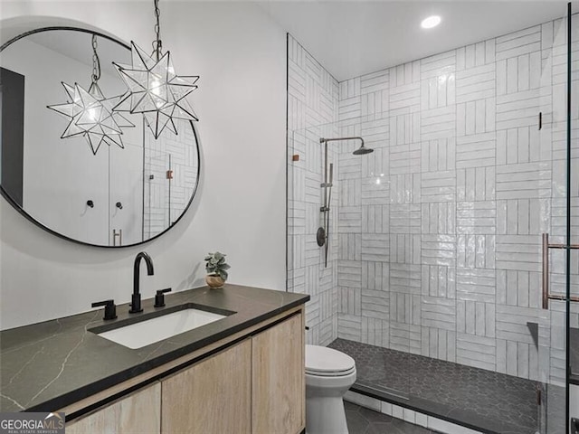 bathroom featuring tiled shower, vanity, and toilet