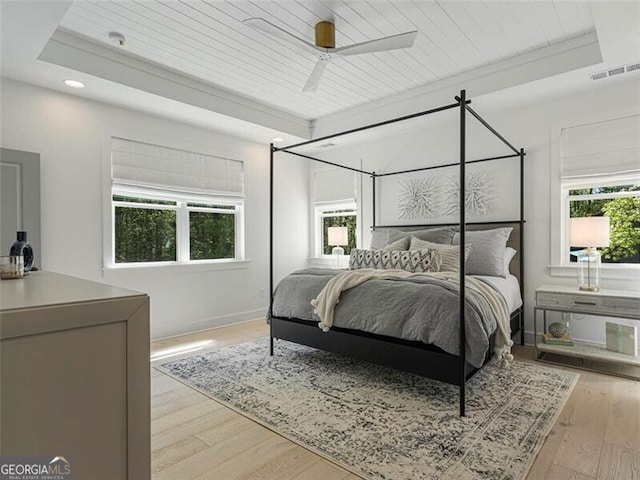 bedroom with light wood-type flooring, wooden ceiling, ceiling fan, and a raised ceiling