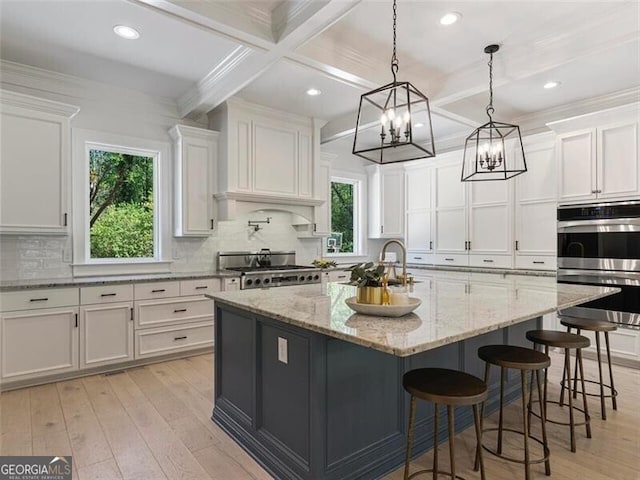 kitchen featuring stainless steel double oven, white cabinetry, sink, and a large island