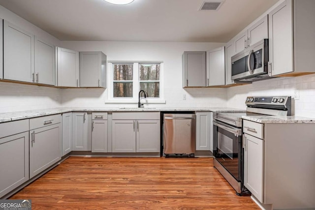 kitchen with gray cabinets, sink, stainless steel appliances, and light hardwood / wood-style floors