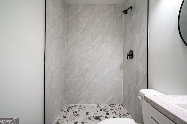 bathroom with a tile shower and vanity