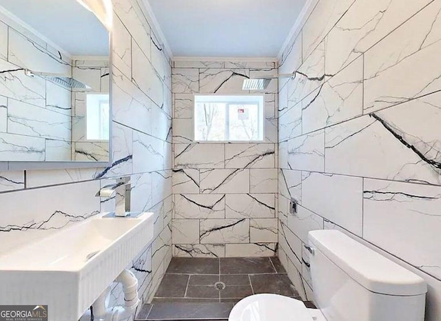 bathroom with a shower, sink, toilet, tile walls, and crown molding