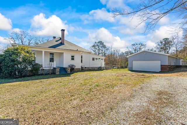 rear view of property with a garage, a lawn, a porch, and an outdoor structure