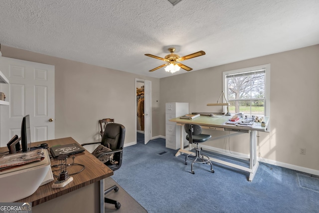 carpeted home office featuring a textured ceiling and ceiling fan