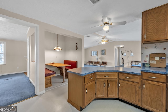 kitchen featuring vaulted ceiling, a textured ceiling, decorative light fixtures, ceiling fan, and kitchen peninsula