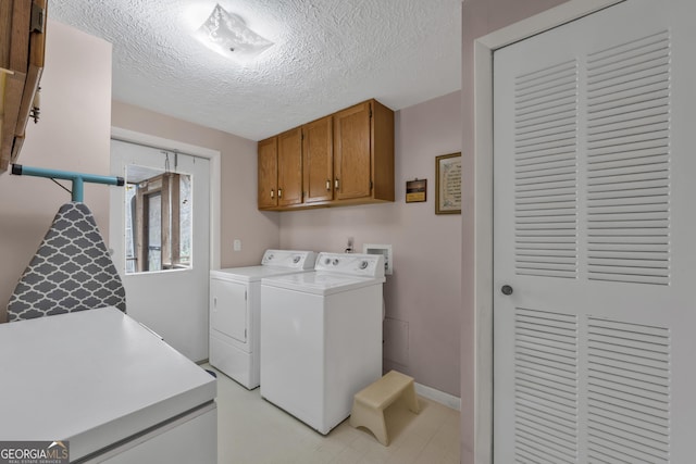 laundry room featuring cabinets, washer and clothes dryer, and a textured ceiling