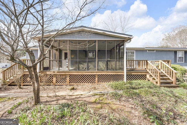 rear view of property with a sunroom and a wooden deck