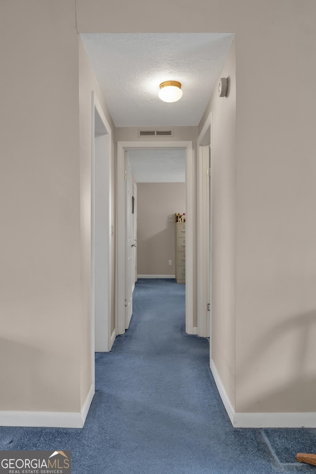 corridor featuring carpet and a textured ceiling