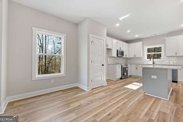 kitchen featuring appliances with stainless steel finishes, backsplash, and light wood finished floors
