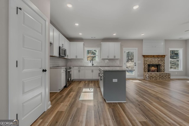 kitchen with light wood-style floors, a center island, stainless steel appliances, open floor plan, and tasteful backsplash