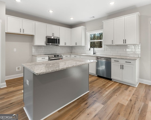 kitchen with baseboards, white cabinets, a sink, backsplash, and stainless steel appliances