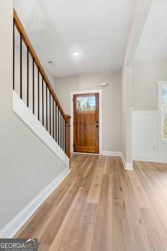 foyer entrance featuring visible vents, wood finished floors, a healthy amount of sunlight, and stairway