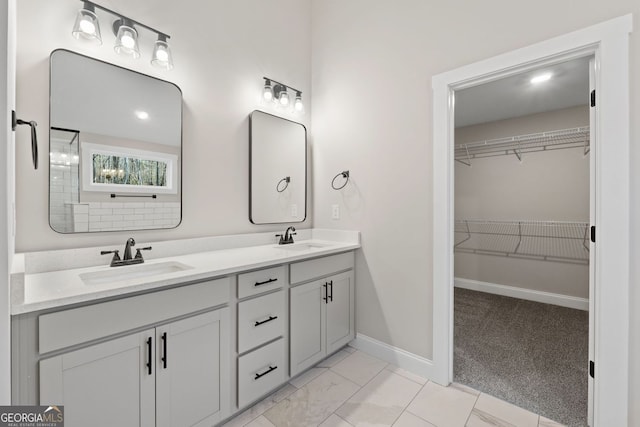 bathroom featuring double vanity, a sink, baseboards, and a spacious closet