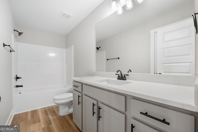 bathroom with vanity, shower / bathtub combination, toilet, wood finished floors, and visible vents