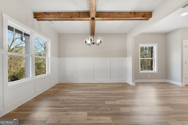 unfurnished dining area with plenty of natural light, light wood finished floors, and a chandelier
